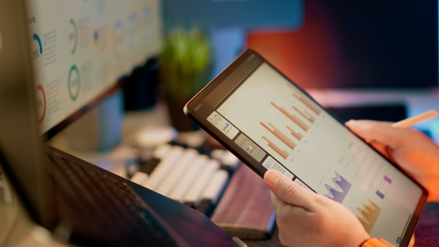 Servizi Persona che analizza grafici aziendali su un tablet alla scrivania.